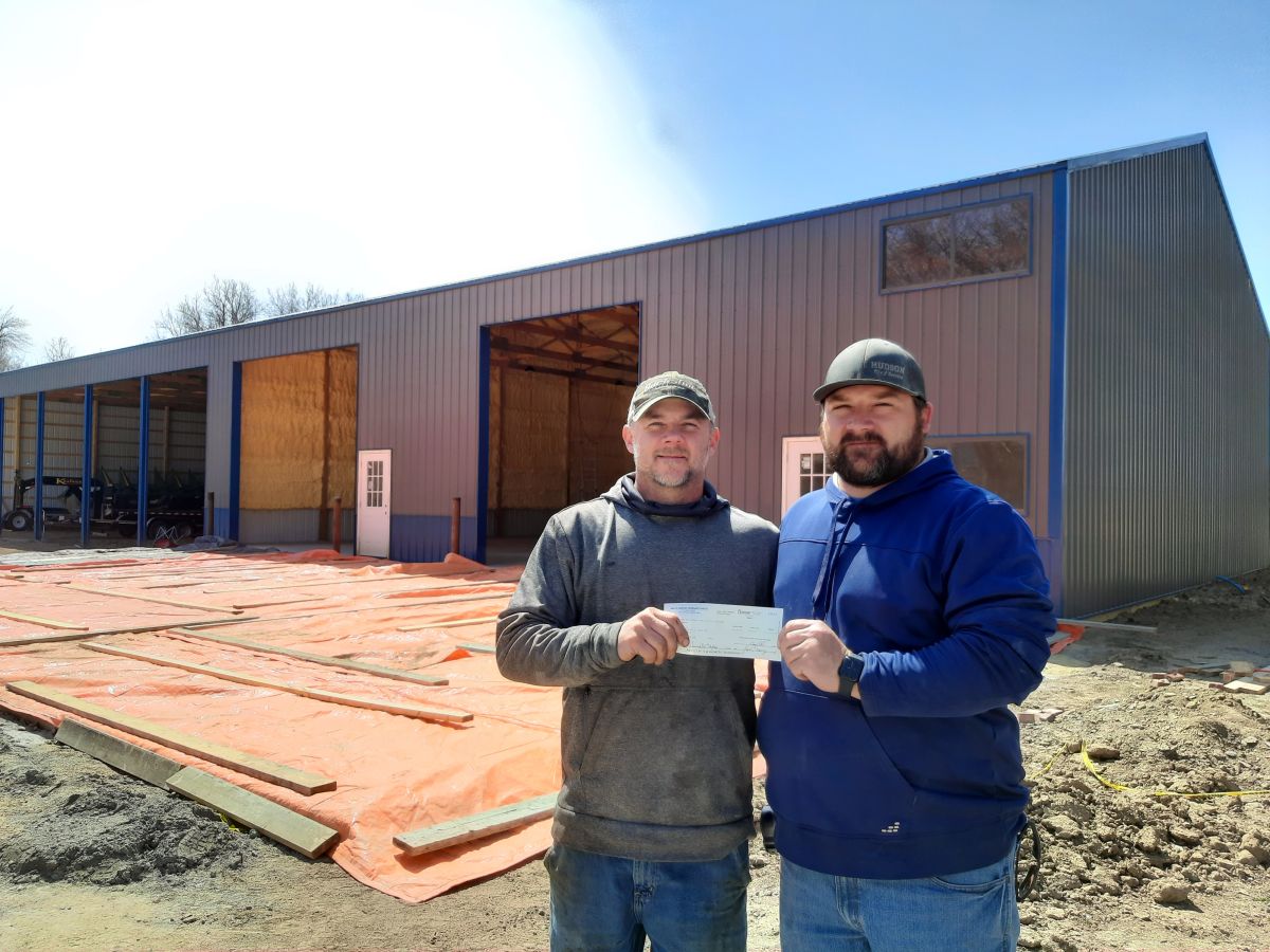 Two men with a check in front of building